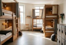 هاستل چیست؟ حریم خصوصی و امکانات مشترک را چگونه مدیریت کنیم؟ تصویر شاخص: نمای مفهومی اتاق اشتراکی هاستل با تختهای جدا و کمدهای شخصی، بدون حضور مهمانان.