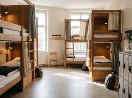 هاستل چیست؟ حریم خصوصی و امکانات مشترک را چگونه مدیریت کنیم؟ تصویر شاخص: نمای مفهومی اتاق اشتراکی هاستل با تختهای جدا و کمدهای شخصی، بدون حضور مهمانان.